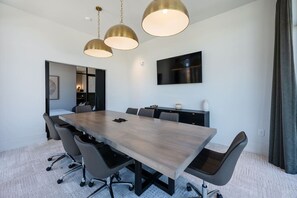 A conference room with a long table, chairs, and pendant lighting. - Chic, New Apt | Pool | Long Stays (Athens)