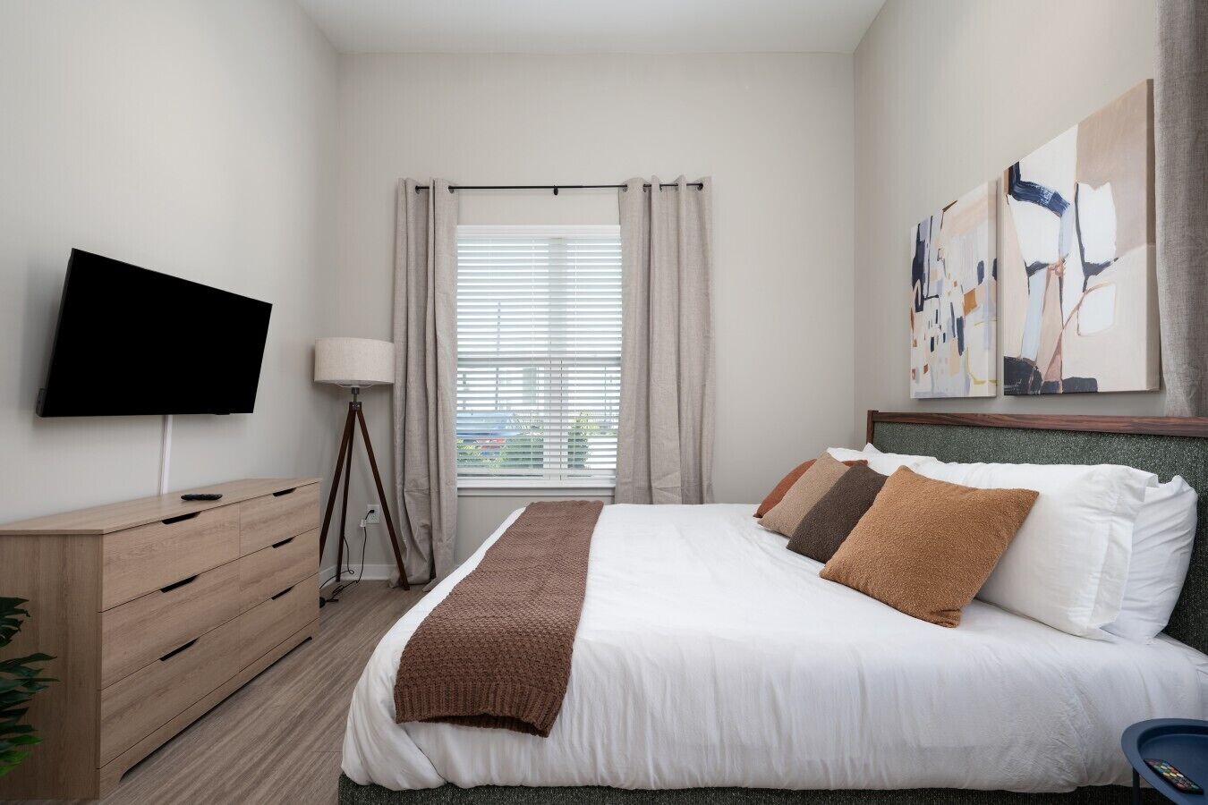 Ein Hotelzimmer mit Bett, Fernseher, Nachttisch, Lampe und einem Bild an der Wand.