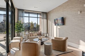 A modern living room with a sofa set, a coffee table, and a TV mounted on the wall. - Chic, New Apt | Pool | Long Stays (Athens)