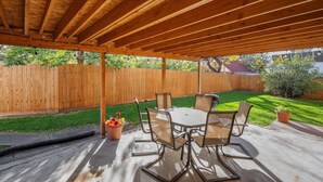 Eine Terrass mit Holzboden, einem Tisch mit Stühlen und einem Holzzaun im Hintergrund.