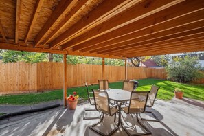 An outdoor patio with a wooden ceiling, a table with chairs, and a wooden fence in the background. - Cozy 4-bedroom home in Cheyenne close to Frontier/Lions Park and downtown (Cheyenne)