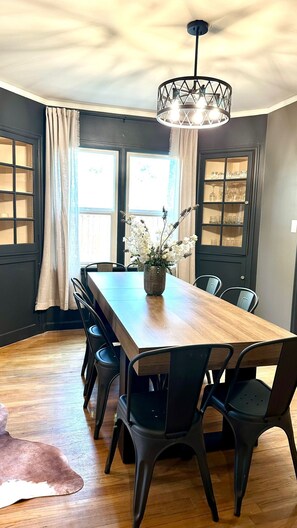 A dining room with a long wooden table, black chairs, a vase with flowers, and a chandelier. - Cozy 4-bedroom home in Cheyenne close to Frontier/Lions Park and downtown (Cheyenne)