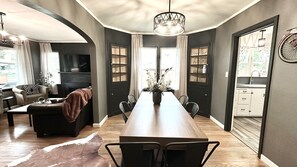 A modern dining area with a long wooden table, black chairs, and a vase of flowers. - Cozy 4-bedroom home in Cheyenne close to Frontier/Lions Park and downtown (Cheyenne)