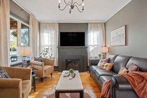 Een woonkamer met een open haard, een bank, een salontafel en een televisie.
