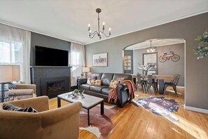 A modern living room with a fireplace, leather sofa, and a dining area with a bicycle wall decoration.