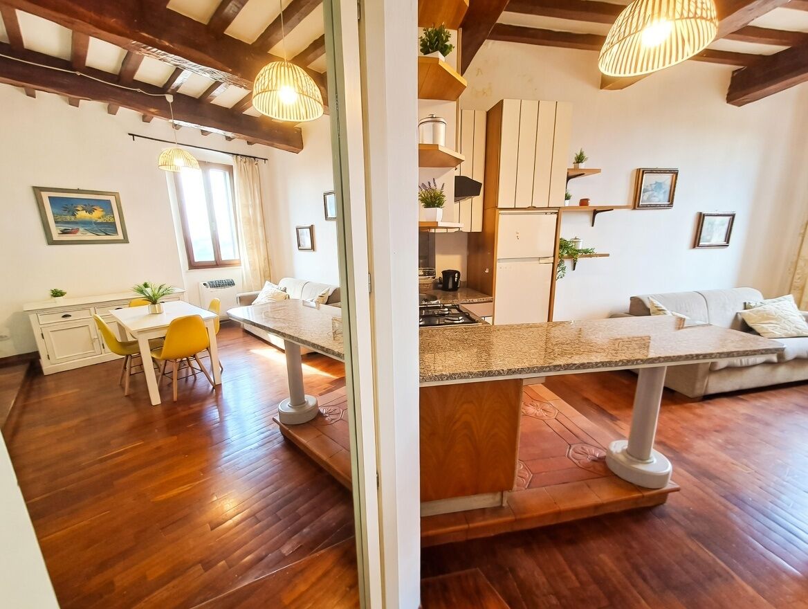 Une cuisine moderne avec un plancher en bois, un coin repas avec des chaises jaunes et un canapé.
