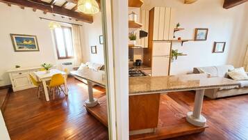 Eine moderne Küche mit Holzboden, einem Essbereich mit gelben Stühlen und einem Sofa.