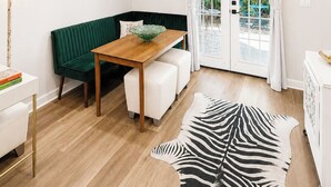 Ett modernt vardagsrum med en grön soffa, ett matbord i trä och en matta med zebrasträck.