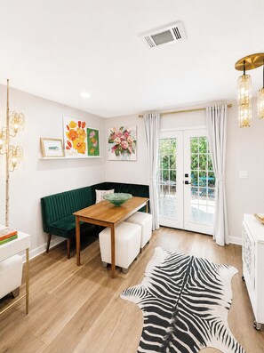 A modern living room with a green sofa, a wooden dining table, and a zebra-patterned rug. - The Cali Belle, Walk to Campus by Velvet Ditch Villas (Oxford)
