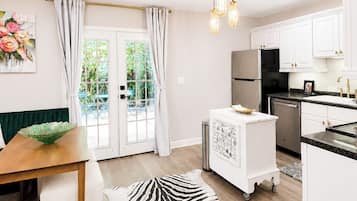 A modern kitchen with white cabinets, a black refrigerator, and a dining area with a wooden table and a zebra print rug.