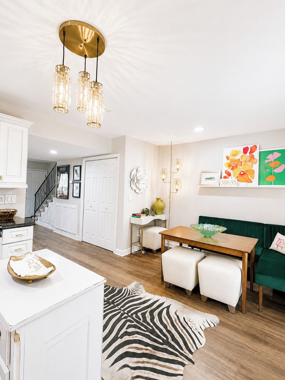 A modern kitchen with white cabinetry, a wooden dining table, and a green sofa.