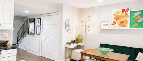 A modern kitchen with white cabinetry, a wooden dining table, and a green sofa.