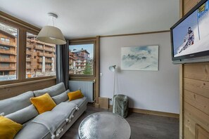 Ein modernes Wohnzimmer mit einer Couch, einer Lampe, einem Fernseher und einem Gemälde.