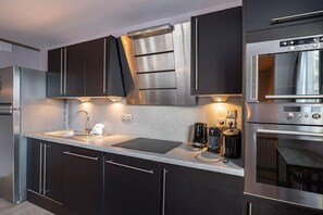 A modern kitchen with stainless steel appliances, a built-in oven, and a coffee maker. - Solaise 202–302 – Stunning Renovated Duplex in the Heart of Val d’Isère (Val-d'Isère)
