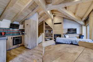 Ein Holzinnenraum mit einer Küche, einem Essbereich und einem Bett.