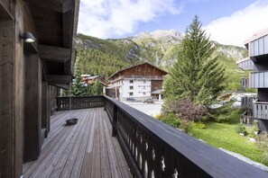 Eine Holzterrasse mit Blick auf eine Berghütte und die umliegenden Bäume.