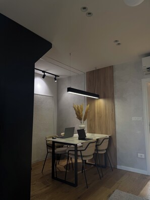 A modern dining area with a table, chairs, and a laptop. - 2BR Skopje Apartment with Cathedral View, In The Main Square (Skopje)