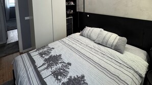 Un dormitorio con cama, armario y estantería empotrada.