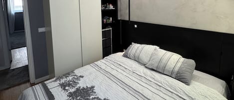 Un dormitorio con cama, armario y estantería empotrada.