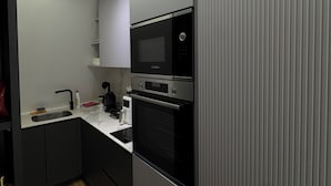 Una cocina moderna con microondas, horno y cafetera integrados en la encimera.