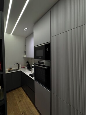 A modern kitchen with a built-in microwave, oven, and a coffee maker on the countertop. - 2BR Skopje Apartment with Cathedral View, In The Main Square (Skopje)