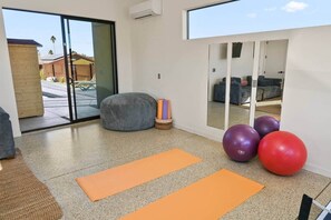 A room with exercise equipment, a sliding glass door leading outside, and a large mirror. - Nightfall | Custom pool, spa, sauna, & game room (Twentynine Palms)