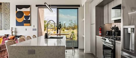 A modern kitchen with a central island, stainless steel appliances, and a view to the outdoors.