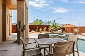 A poolside area with a table and chairs, a cactus, and a wooden fence.