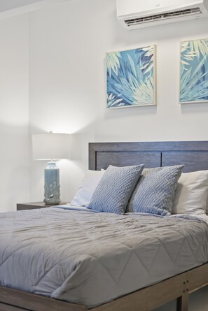 Une chambre à coucher avec un lit, une table de chevet, une lampe et des œuvres d’art murales.