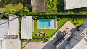 A rooftop pool with a clear blue water feature, surrounded by a well-maintained lawn and seating area. - Brisamare Apt 5 | 2BR | Pool, BBQ, Generator (San Juan)