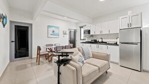 A modern apartment with a dining area, kitchenette, and a sofa with a coffee table. - Brisamare Apt 5 | 2BR | Pool, BBQ, Generator (San Juan)