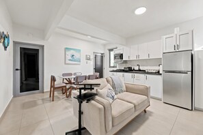 A modern apartment with a dining area, kitchenette, and a sofa with a coffee table. - Brisamare Apt 5 | 2BR | Pool, BBQ, Generator (San Juan)