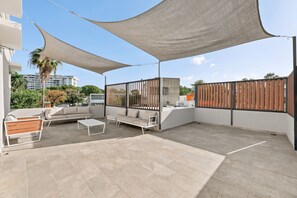An outdoor patio with a sofa, chairs, and a table. - Brisamare Apt 5 | 2BR | Pool, BBQ, Generator (San Juan)