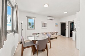 Ein modernes Wohnzimmer mit Essbereich, einer Couch, einem Couchtisch und einem Fernseher.
