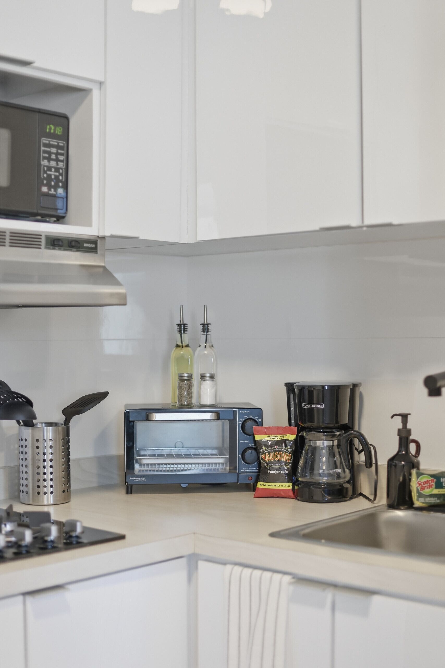 Una cucina accessoriata con forno a microonde, tostapane, macchina del caffè e diversi utensili da cucina.