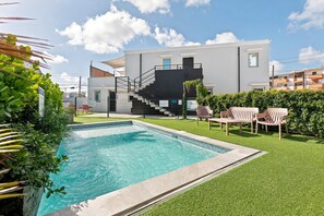 Ein modernes Wohngebäude mit Schwimmbad, Treppe und Sitzgelegenheiten im Freien.