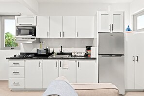 A modern kitchen with white cabinets, a microwave, a stove, and a refrigerator. - Brisamare Collection | Pool | Sleeps 14 (San Juan)
