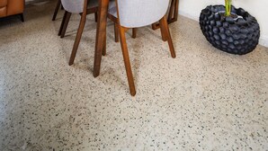 Un espace repas comprenant une table et des chaises, un ventilateur de plafond, un tableau accroché au mur et une plante en pot.