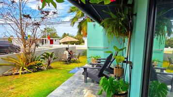 Eine Terrassenfläche mit Tisch und Stühlen, einem Blumentopf und Blick auf die Straße.
