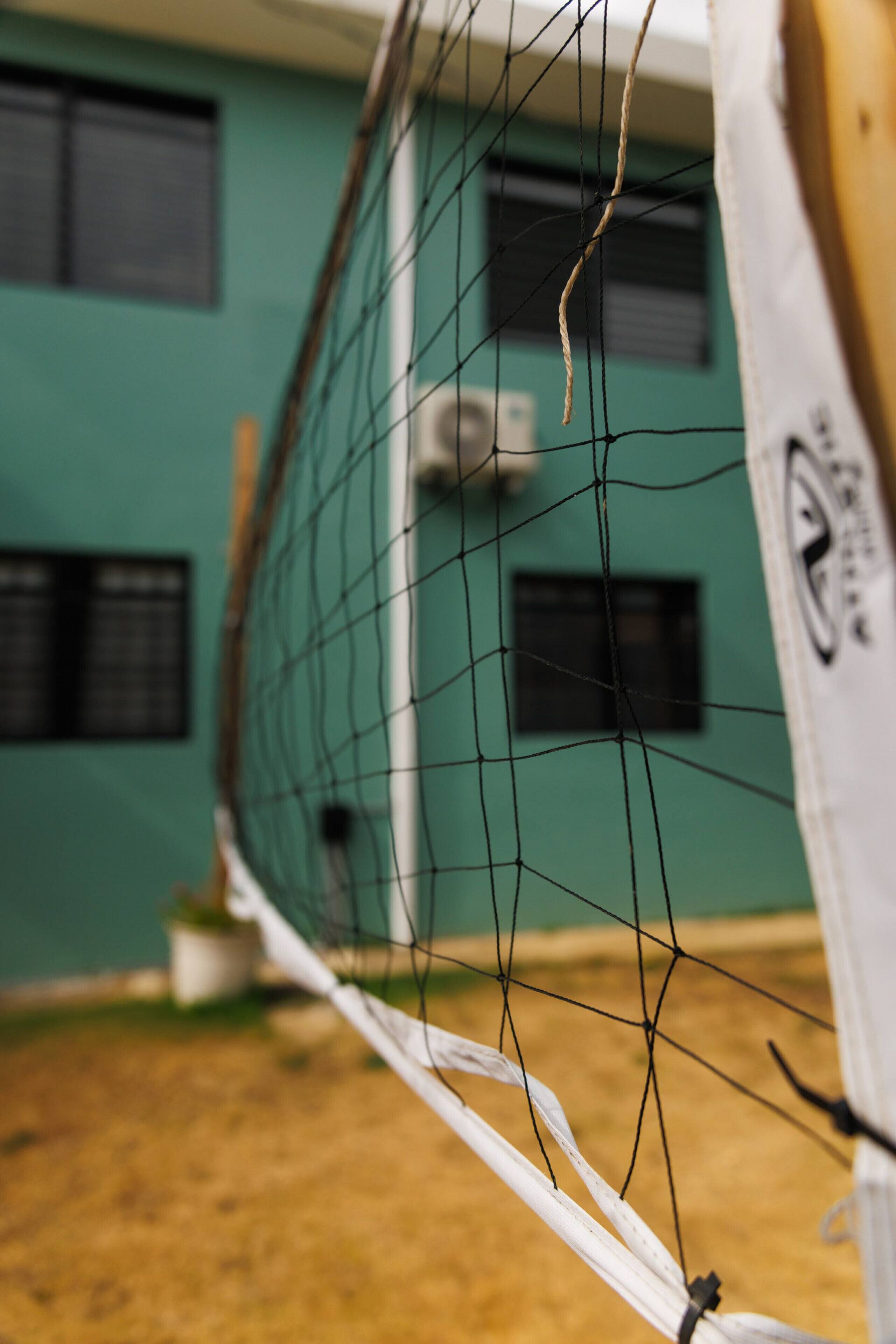 Ein Detailaufnahme eines Volleyballnetzes, im Hintergrund ein Gebäude.