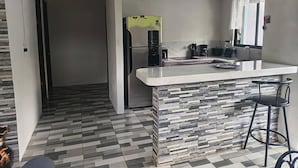 A modern kitchen with a built-in island, a refrigerator, and bar stools. - Villa Alomía, Private Pool, 10 People (Cahuita)