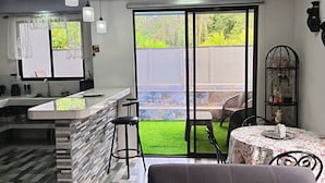 A modern kitchen with a central island, bar stools, and a dining area with a table and chairs. - Villa Alomía, Private Pool, 10 People (Cahuita)