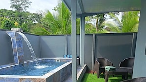 A spa area with a hot tub, artificial grass, wicker furniture, and a water feature. - Villa Alomía, Private Pool, 10 People (Cahuita)