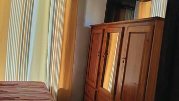 Une chambre à coucher avec un lit, une armoire en bois et des rideaux.