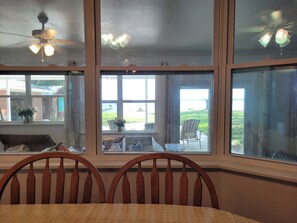 A dining area with a table, chairs, and a view of the outdoors through large windows.