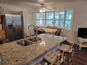 Una cocina moderna con encimera de granito, electrodomésticos de acero inoxidable y una zona de comedor con mesa y sillas.