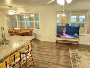 Una cocina con una mesa de comedor, sillas, un televisor y suelo de madera.