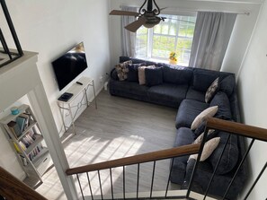 A modern living room with a sectional sofa, a flat-screen TV, a small side table, and a bookshelf. - Spacious 4-bedroom Monthly Stay Cozy house with AC in terrific Arlington TX (Arlington)