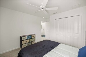 A bedroom with a bed, a ceiling fan, a dresser, and a closet. - Spacious 3BR · Sleeps 7 · King Bed · Lanai (Okahumpka)