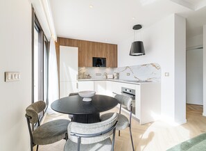 A modern kitchen with white cabinetry, a marble backsplash, and a black pendant light. - Mamabaldi Apartment – Elegance, tranquility and views from the top of Nice (Nice)